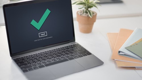Laptop displaying a green tick on the screen, symbolising a successful verification