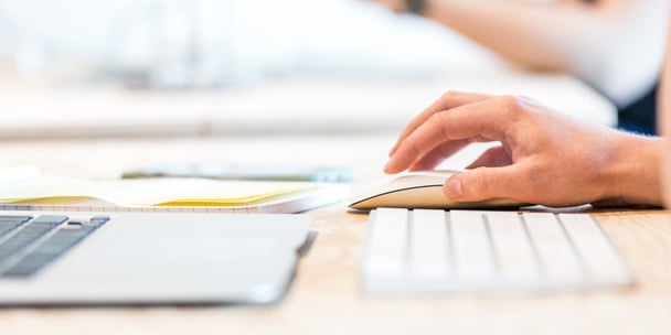 Person using a laptop with a mouse and keyboard